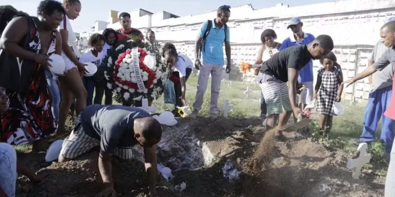 Na foto, Mike Oliveira Ramos com a pá enterrando a própria filha — Foto: Domingos Peixoto / Agência O Globo