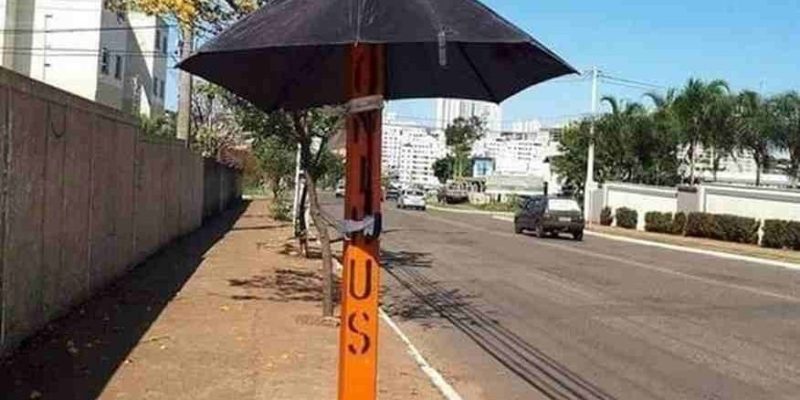 Em alguns locais, postes de energia se tornam pontos de sombra para aguardar o embarque - Imagens - Reprodução