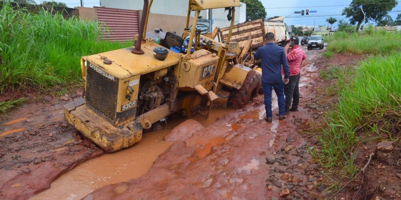 Trator que iria espalhar o cascalho na via tentou rebocar o caminhão e terminou com uma das rodas engolida