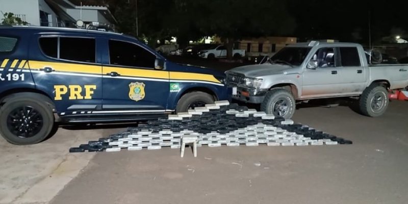 Tabletes de cocaína e ao fundo a caminhonete em que drogava estava sendo levada (Foto: Divulgação)