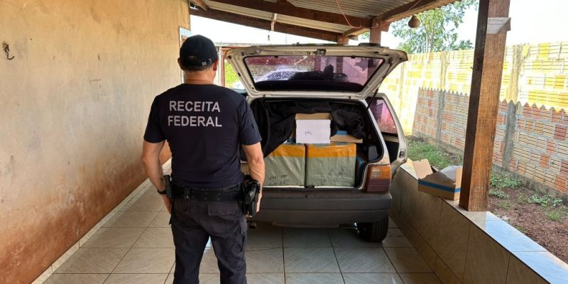 Agente da Receita Federal ao lado de carro lotado com produtos contrabandeados (Foto: Divulgação)