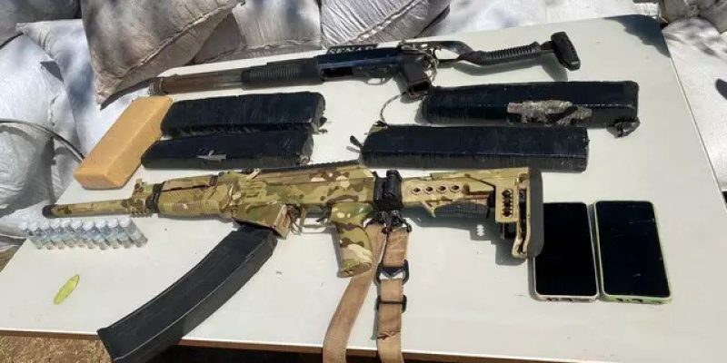Escopetas e carregadores encontrados com brasileiro; ao fundo, bolsas de maconha