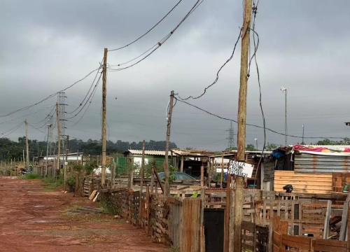 Moradias da comunidade são cercadas por postes de madeira e fiação improvisada (Foto: Victória Costacurta)