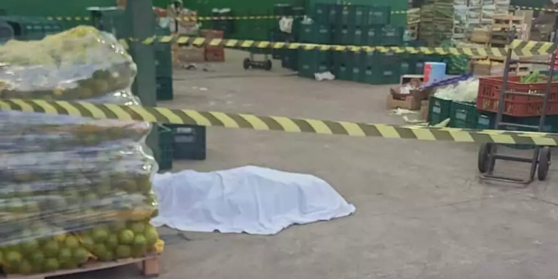 Corpo da vítima ao lado de palete de laranjas no local onde crime aconteceu (Foto: Direto das Ruas)