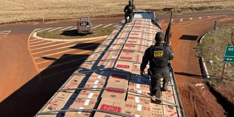 Policiais sobre carreta lotada de cigarro paraguaio (Foto: DOF/Divulgação)