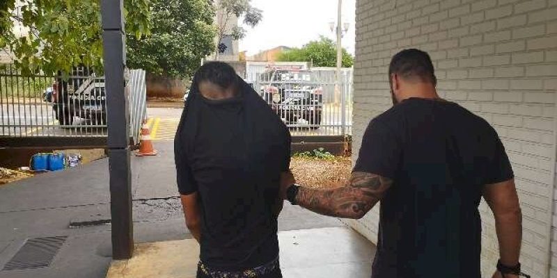 Envolvido em assassinato é conduzido por policial após se apresentar em delegacia (Foto: Leandro Holsbach)