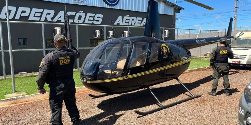 Policiais ao lado do helicóptero, trazido para a sede do DOF em Dourados (Foto: DOF/Divulgação)