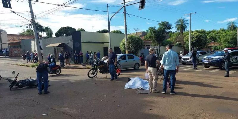 Corpo de Márcio coberto por lençol branco; perícia e delegado ao lado apurando acidente (Foto: Murilo Medeiros)