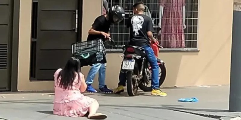 Mulher caída no chão e bandidos roubando a moto — Foto: G1