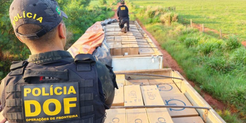 Policiais sobre carreta bitrem lotada de cigarro paraguaio (Foto: DOF/Divulgação)